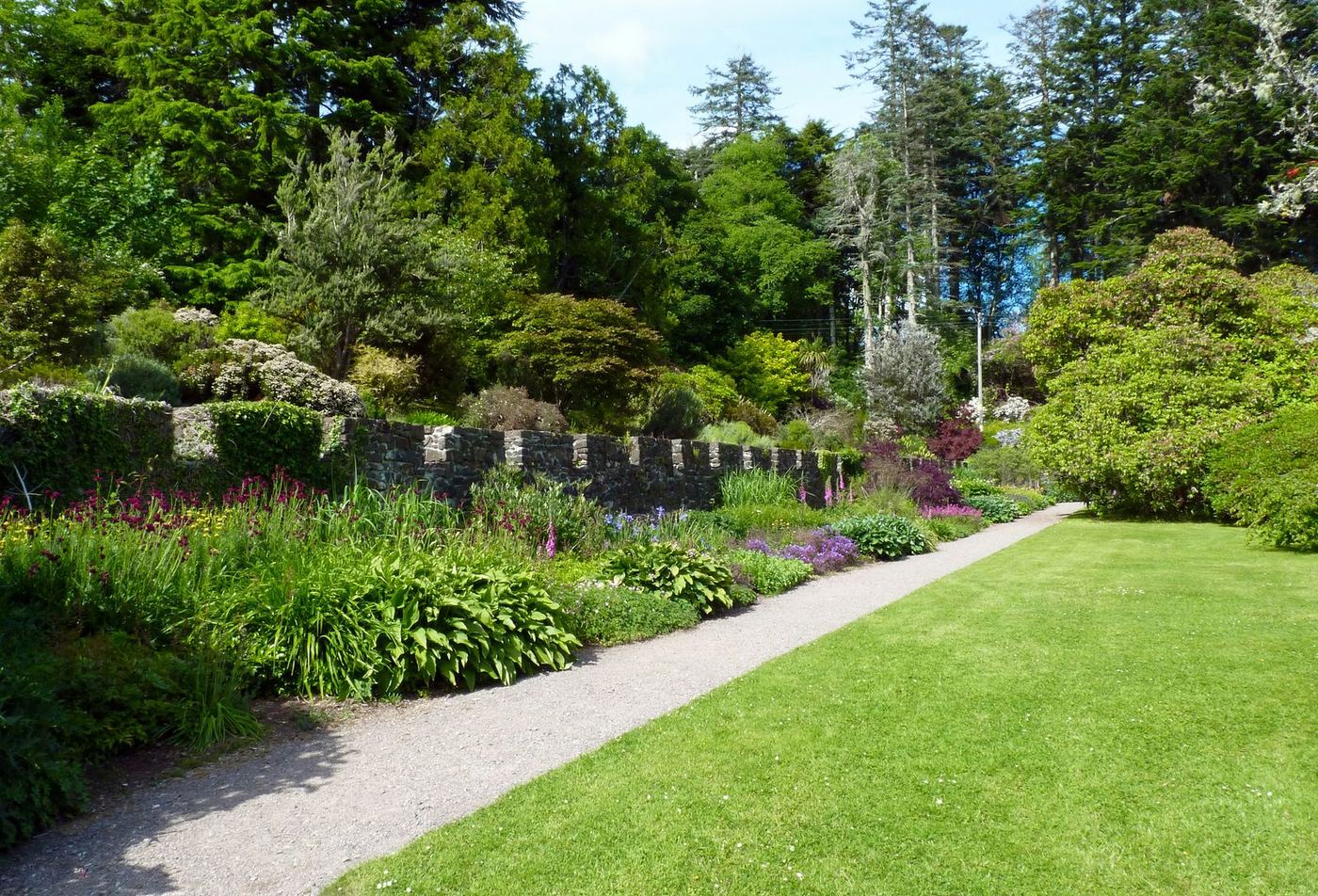 Manicured garden path with lush flower borders and stone wall