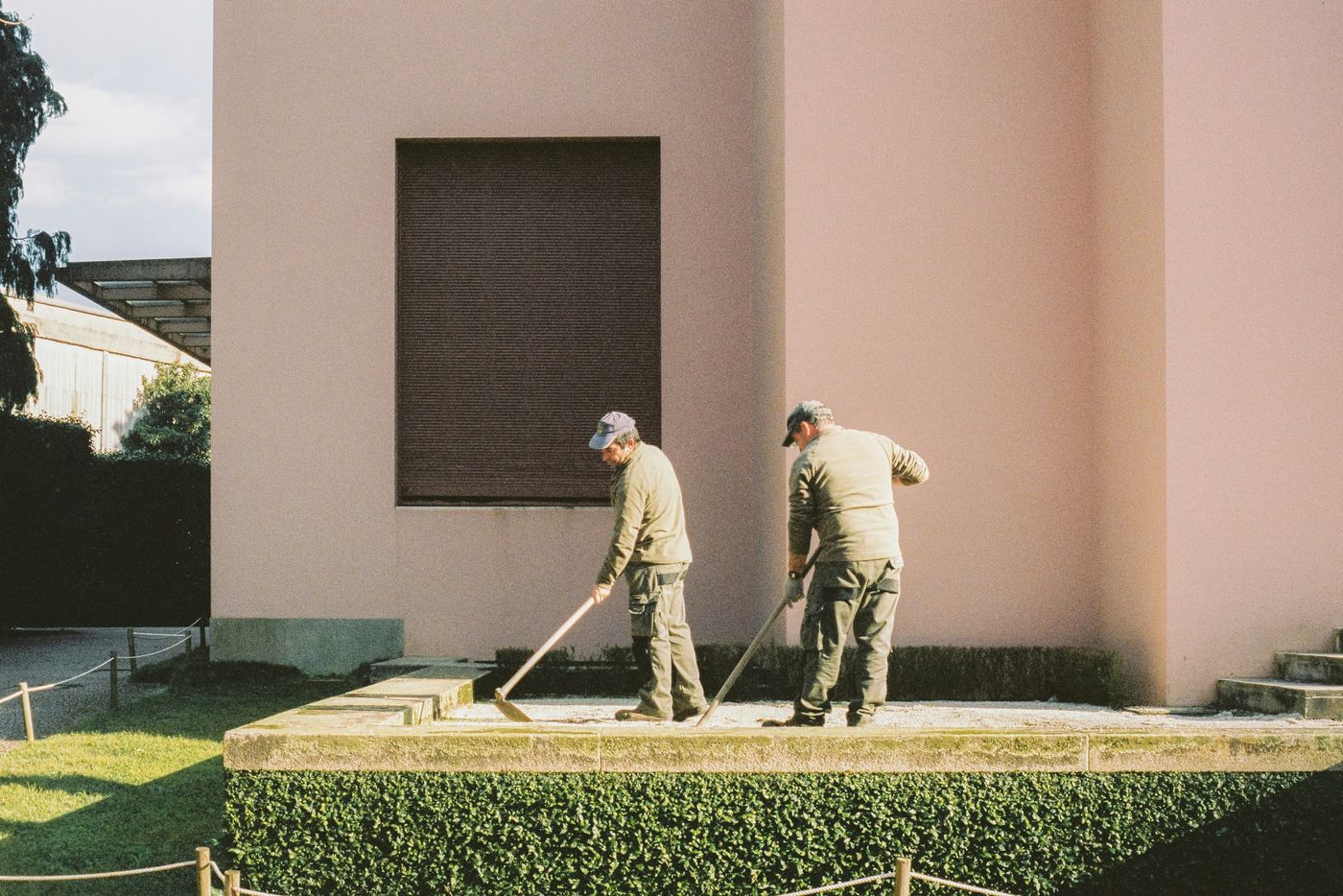 Two-person crew raking and finishing stone work at golden hour